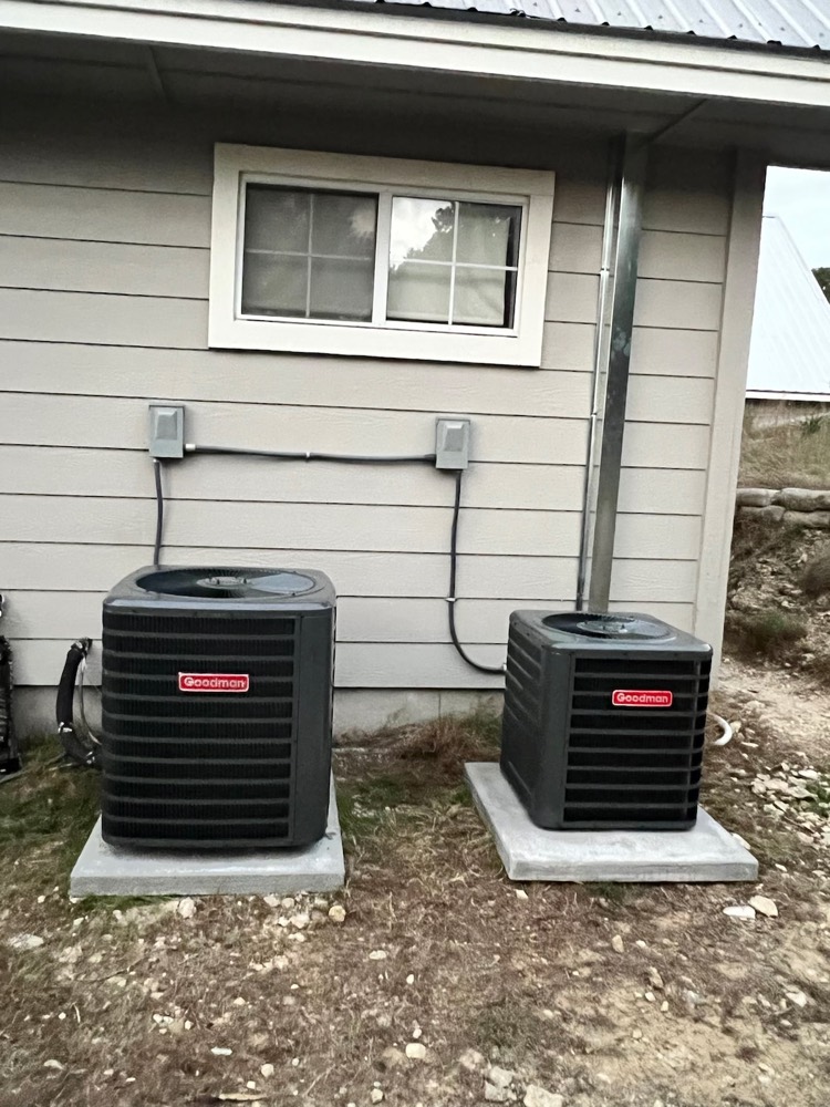 Two Goodman outdoor condenser units on concrete pads